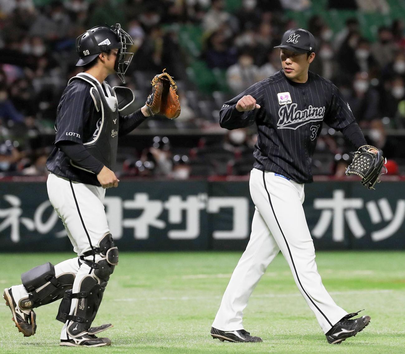 9回に登板し三者凡退に抑え、捕手柿沼（左）とタッチを交わすロッテ・八木（共同）