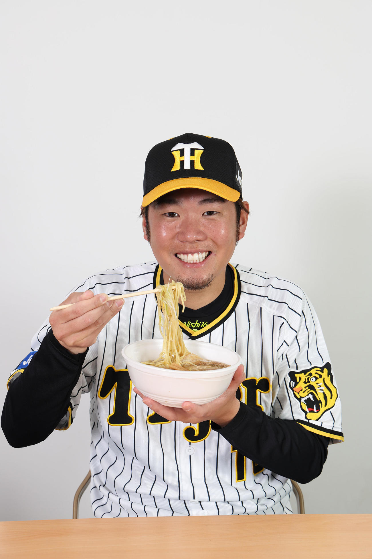 勇ちゃんの背脂醤油ラーメンを食べる西勇（甲子園球場提供）