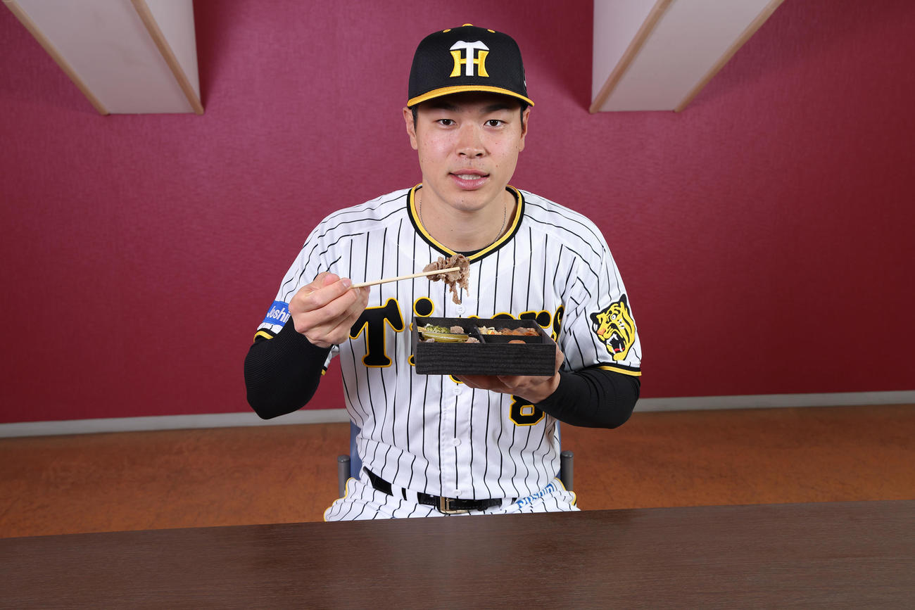 サトテルのトリプル牛肉弁当を食べる佐藤輝（甲子園球場提供）