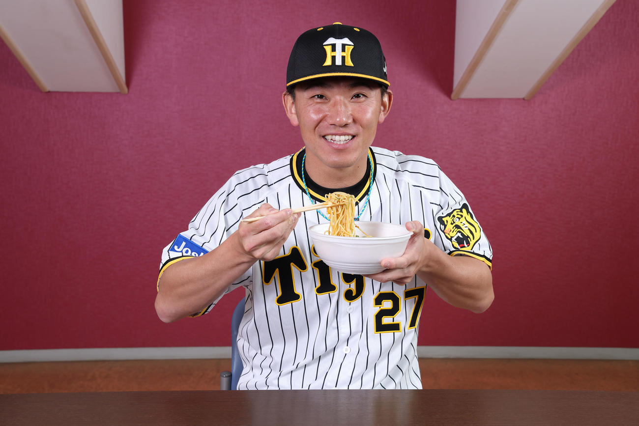 伊藤将司のとろ～りチーズ担々麺を食べる伊藤将（甲子園球場提供）