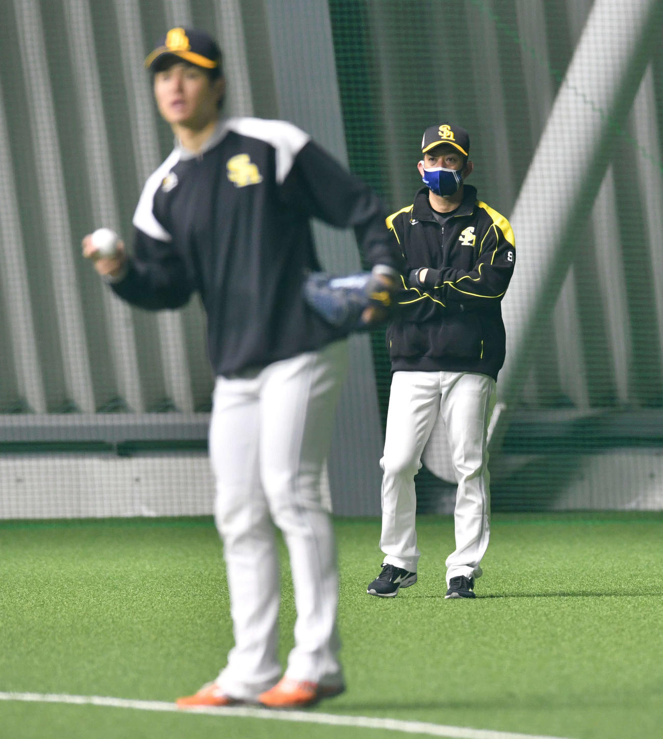 キャッチボールを行うソフトバンク高橋礼（手前）を見つめる佐久本コーチ（2022年2月2日撮影）