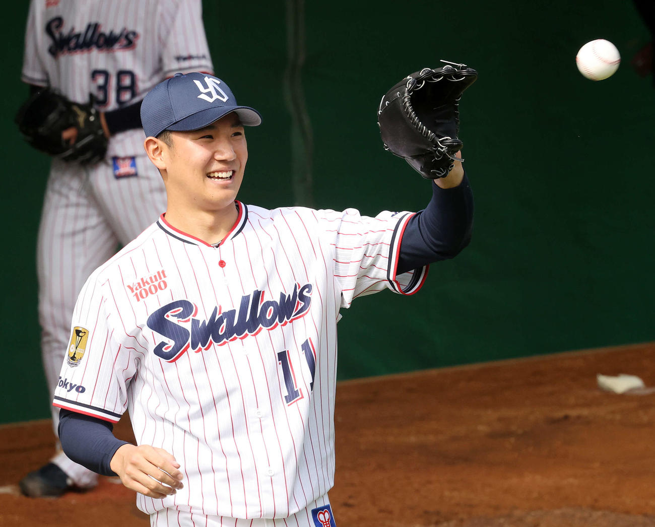 ヤクルト春季キャンプ　ブルペンで投球練習中、笑顔を見せる奥川恭伸＝2022年2月1日
