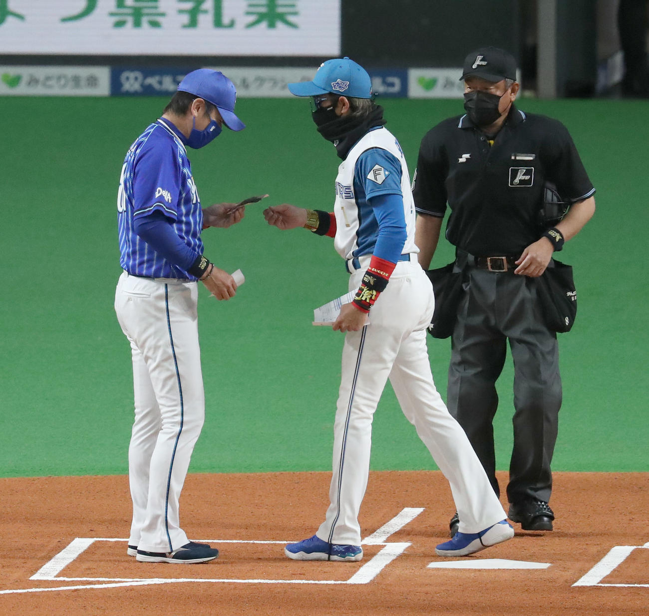 19日、日本ハム対DeNAの試合前、メンバー表を交換する際にDeNA三浦監督（左）に何かを手渡す日本ハム新庄監督