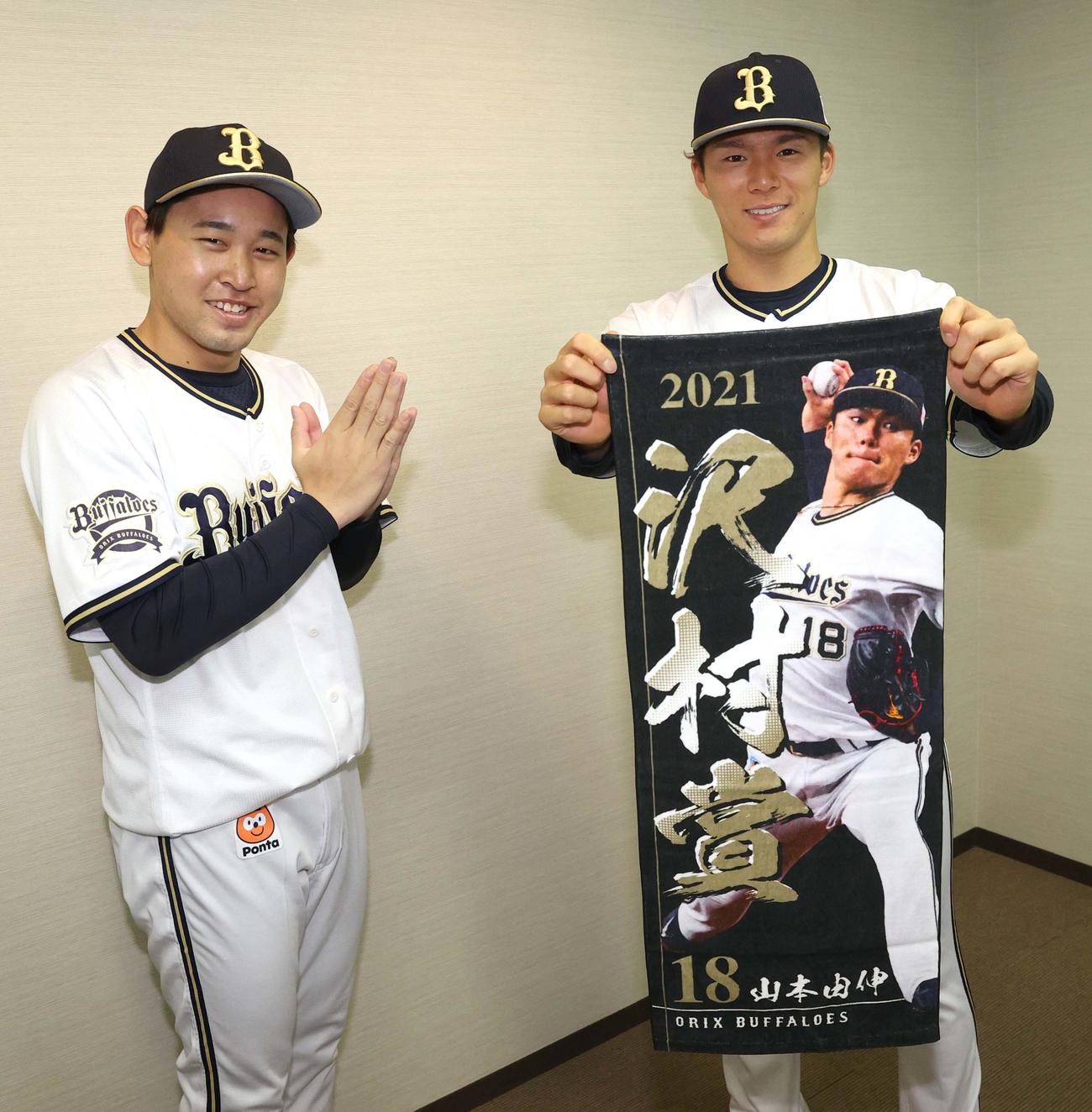 山本は沢村賞受賞タオルを手に笑顔を見せる。左は山本を拝む宮城（撮影・上田博志）
