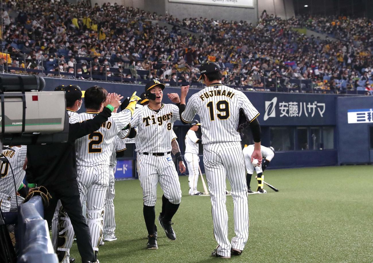 阪神対ヤクルト　3回裏阪神2死二、三塁、糸原の適時三塁打で生還した佐藤輝（中央）は、藤浪（右）らの出迎えを受ける（撮影・上田博志）