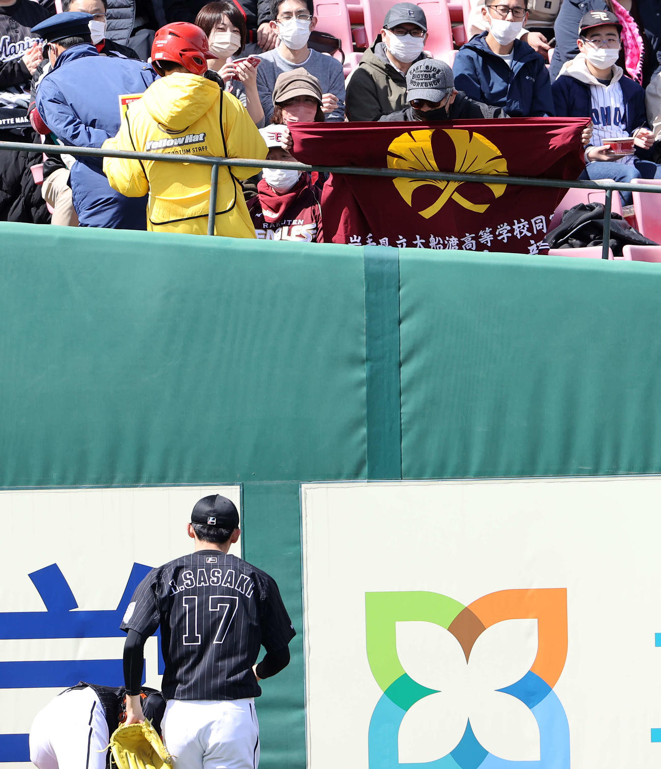 楽天対ロッテ　試合前、スタンドで大船渡高校の旗を掲げるファンとそれを見上げるロッテ佐々木朗（撮影・鈴木正人）