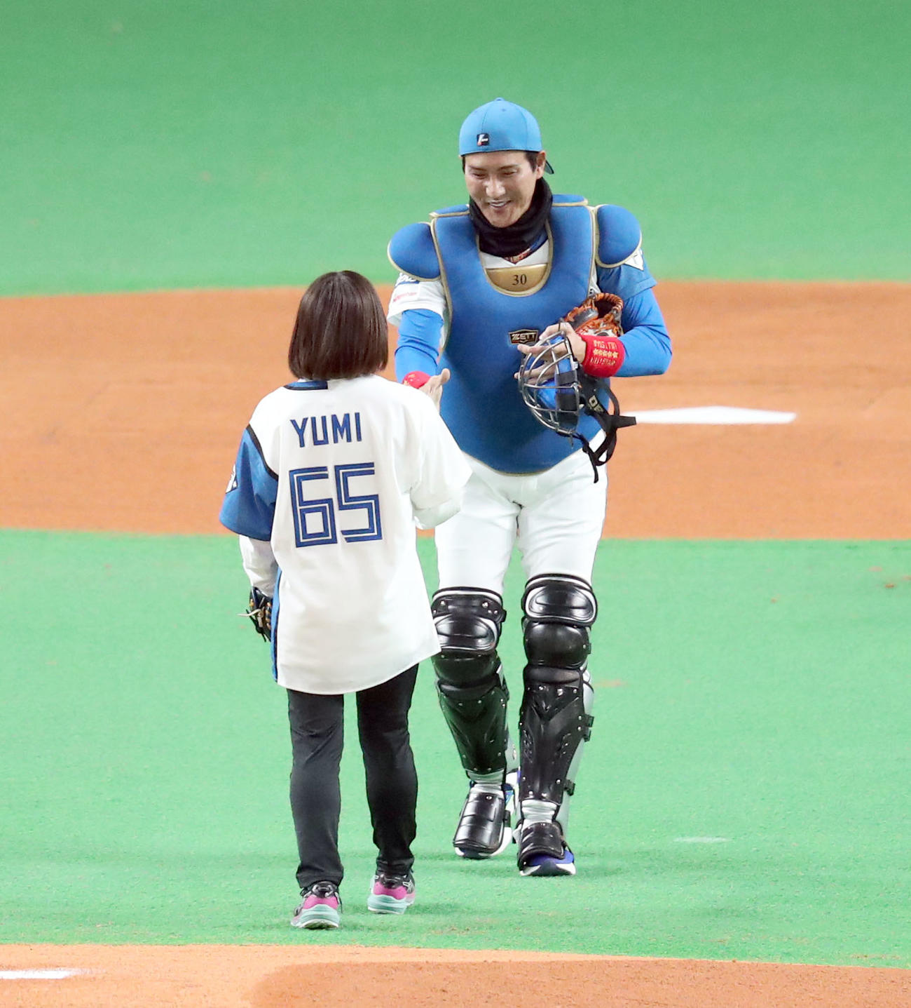 日本ハム対西武　ファーストピッチセレモニーを終え笑顔でロコ・ソラーレの鈴木にボールを手渡す日本ハム新庄監督（右後方）（撮影・佐藤翔太）