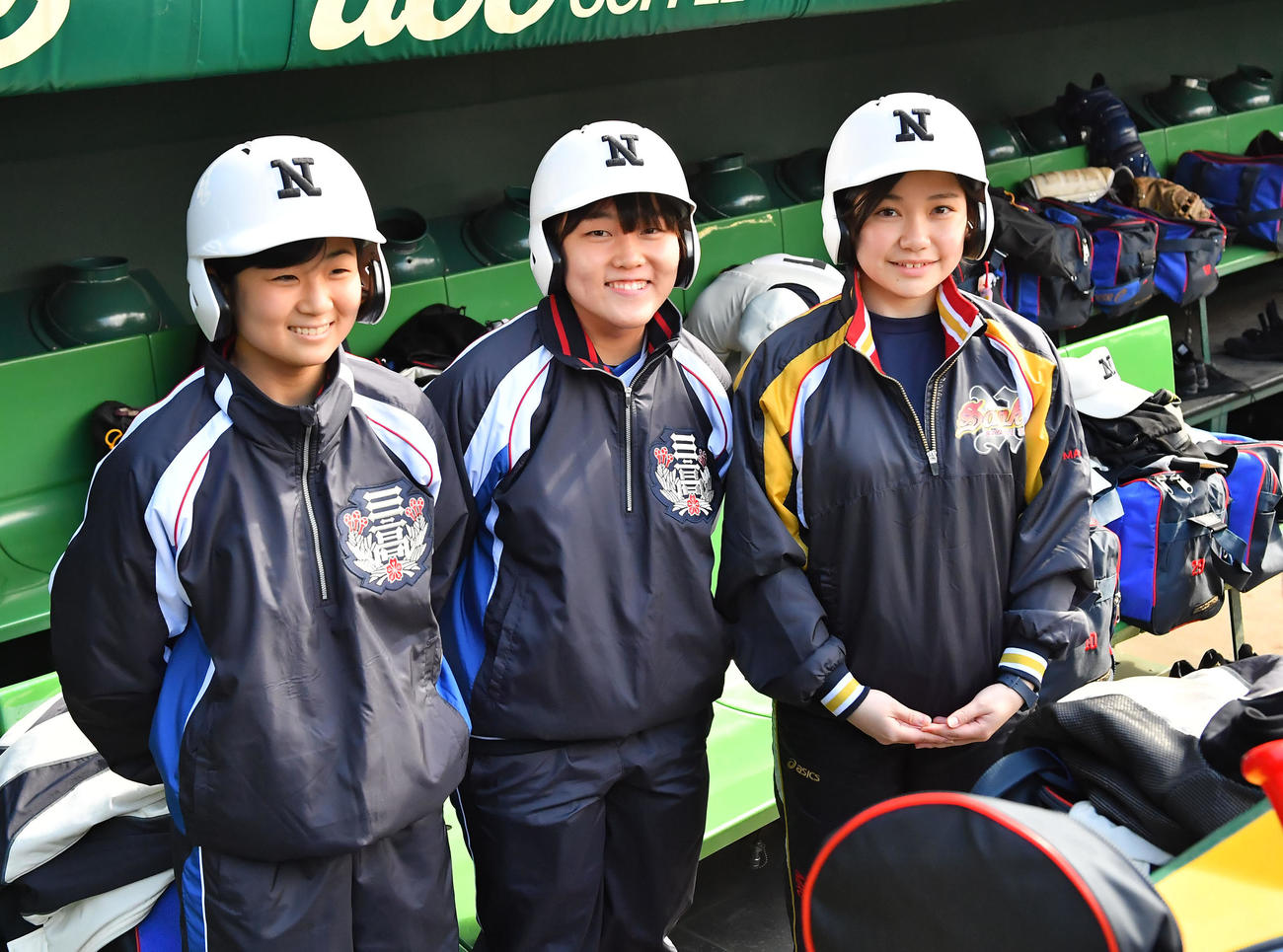 2017年3月15日、卒業間近の３年次にセンバツに同行。甲子園のベンチで笑顔を見せる日大三女子マネジャーの、左から山村友美子さん、佐藤里音さん、高橋真央さん