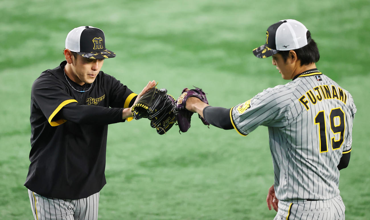 巨人対阪神　試合前、キャッチボールを終えグラブタッチを交わす阪神小川（左）と藤浪（撮影・垰建太）