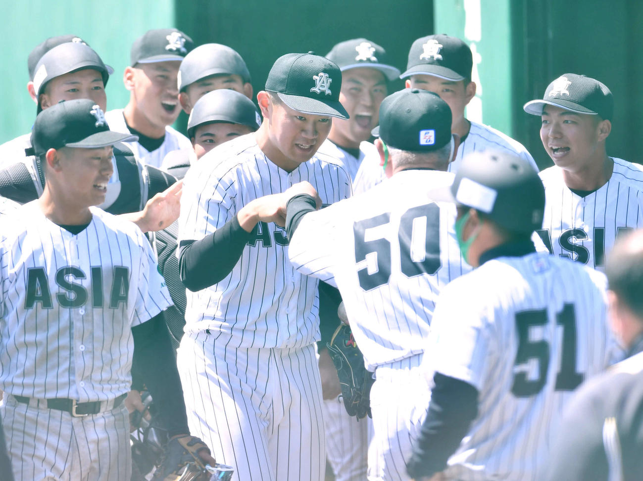 亜大対駒大　完封勝利を挙げた亜大・青山（中央）は、生田監督（背番号50）とグータッチを交わす（撮影・岩下翔太）