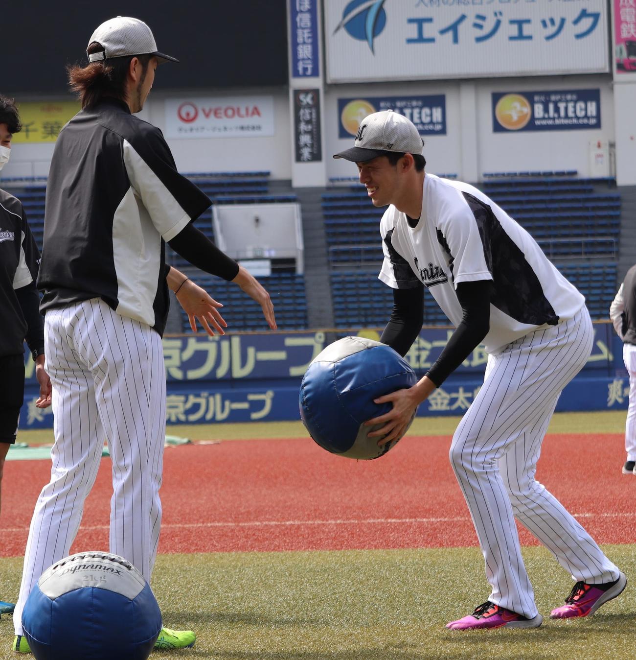メディスンボールを使ったトレーニングで笑顔を見せるロッテ佐々木朗（右）。左は石川（撮影・古川真弥）