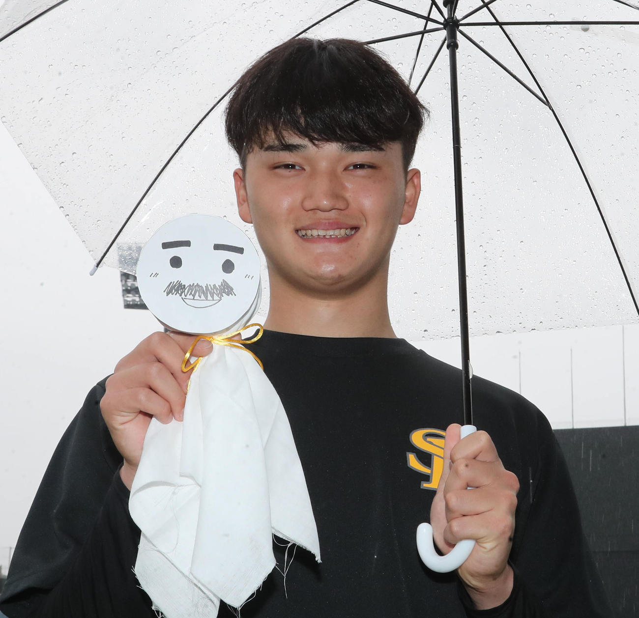 明日は晴れるかな。藤本監督の似顔絵てるてる坊主を手に笑顔を見せる田上奏大（撮影・梅根麻紀）