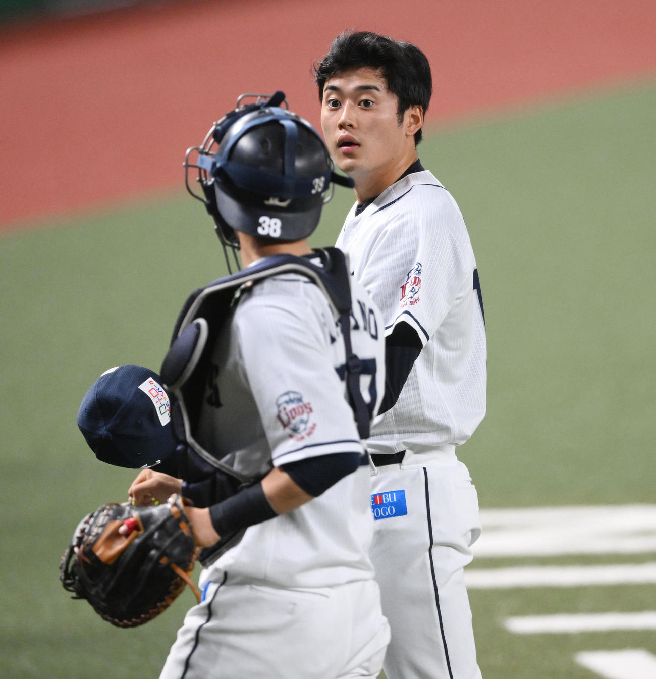 西武対日本ハム　1回表を投げ終え、西武の捕手牧野（手前）と引き揚げる佐藤（撮影・滝沢徹郎）