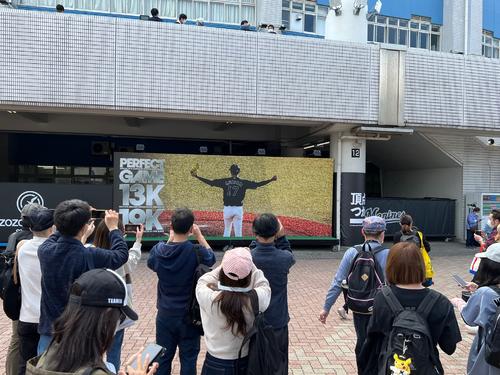 ZOZOマリンに設置されたロッテ佐々木朗の完全試合記念ボードで写真撮影するファン(撮影・金子真仁)