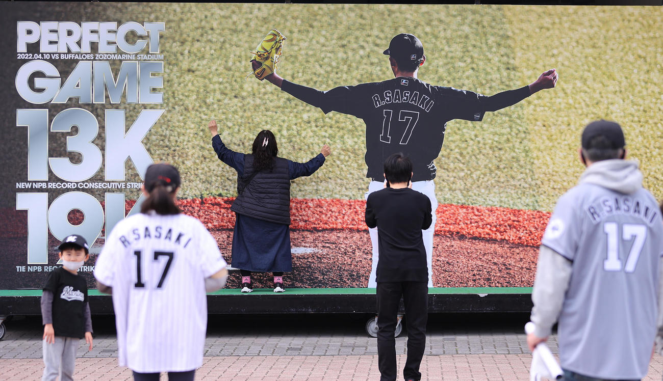 ロッテ対日本ハム　開場前、ロッテ佐々木朗の完全試合達成の記念ボードの前で記念写真を撮るファン（撮影・垰建太）
