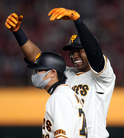 巨人対広島　5回裏巨人無死一塁、右前打を放ち、ベンチに向かって笑顔を見せる巨人ポランコ（後方）。手前は亀井外野守備兼走塁コーチ（撮影・狩俣裕三）