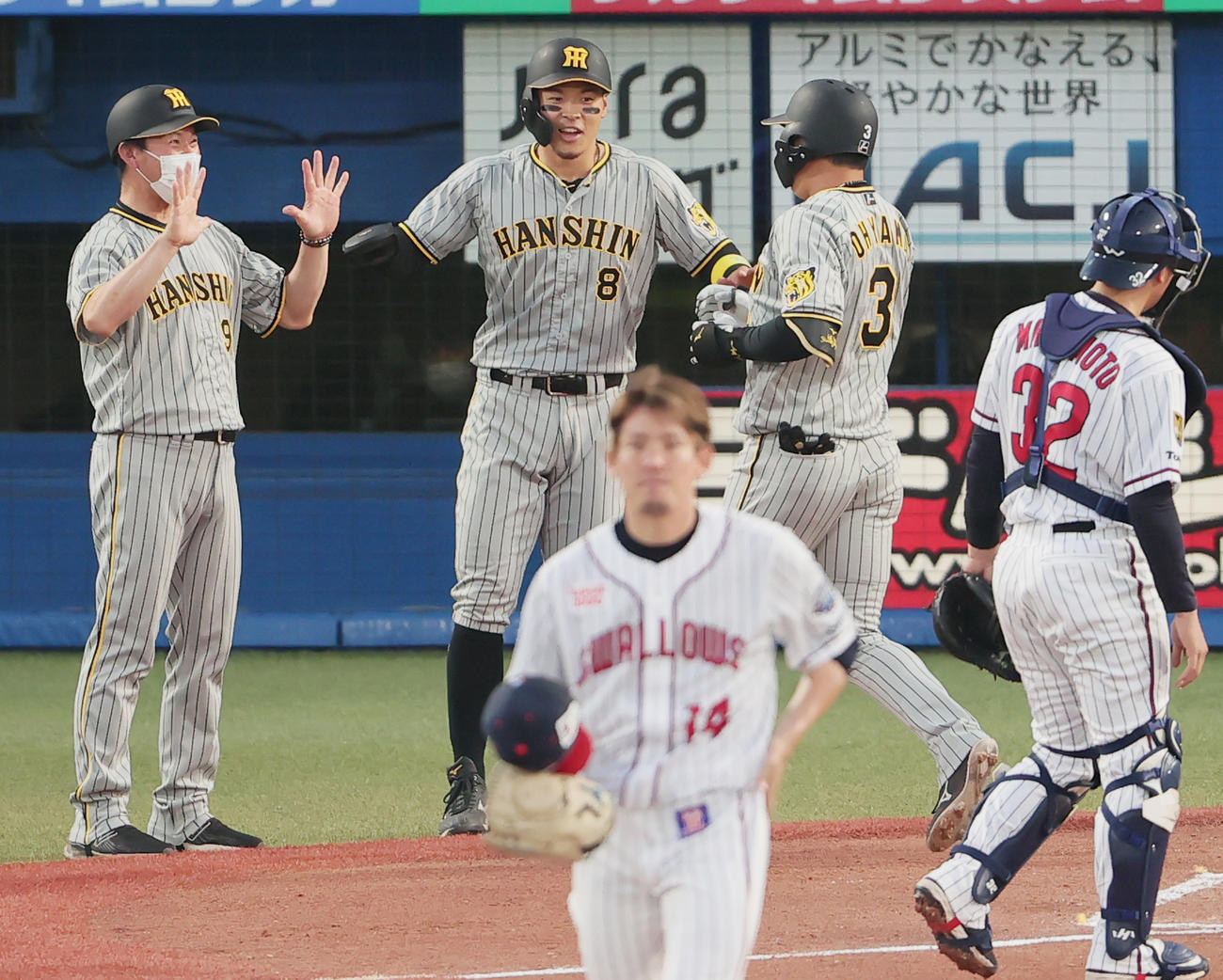 ヤクルト対阪神　1回表阪神2死二塁、高梨（手前）から左越え先制2点本塁打を放った大山（奥右）は奥左から筒井コーチ、佐藤輝に迎えられる（撮影・野上伸悟）
