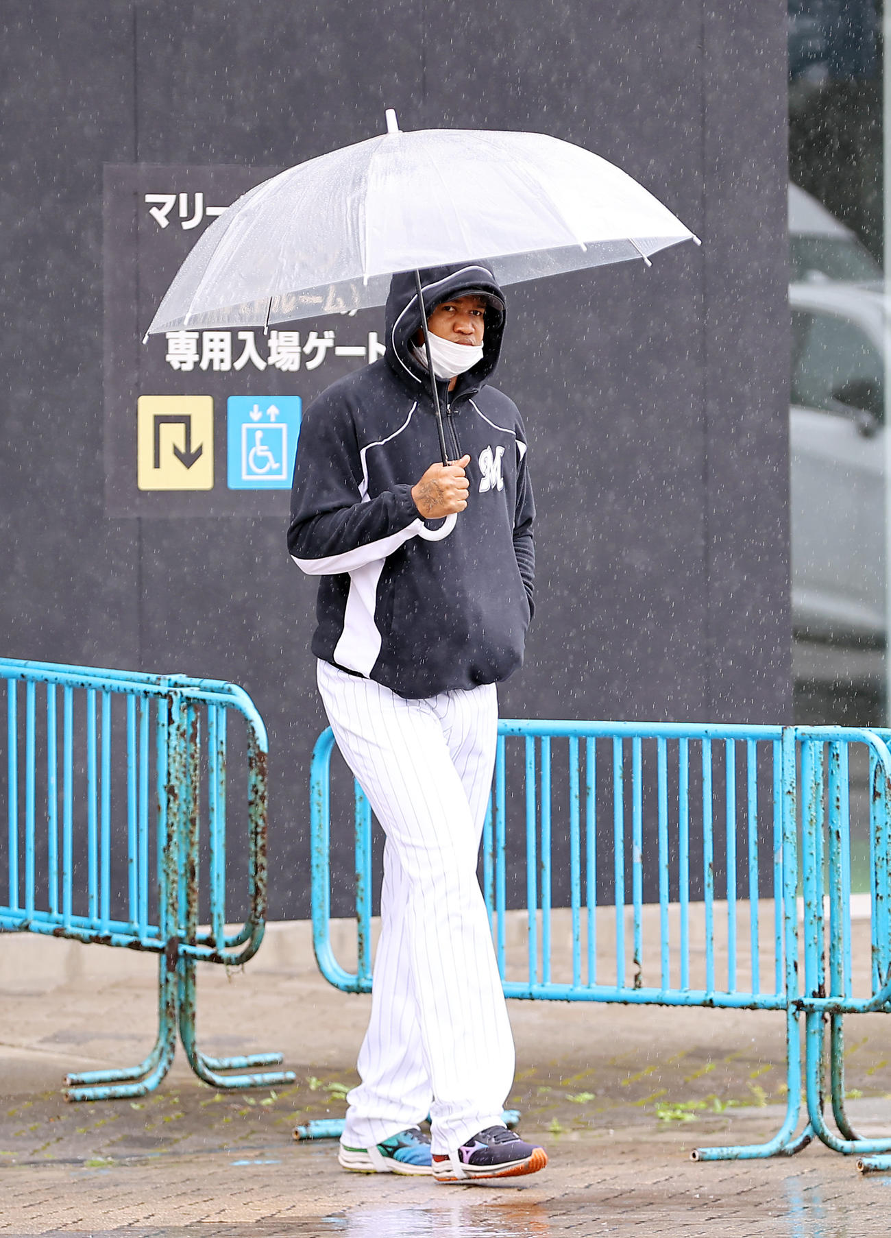 雨天中止となり、傘を差して室内練習場へ移動するロッテのロメロ（撮影・垰建太）