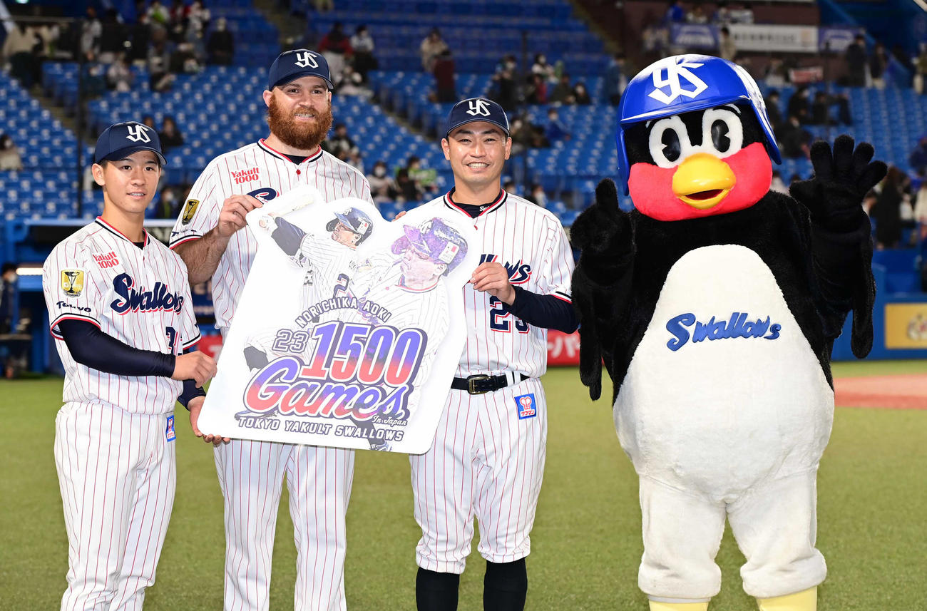 ヤクルト対DeNA　ヤクルト青木（左から3人目）の通算1500試合出場達成の記念ボードを手に記念撮影する、左から内山壮、サイスニード、1人おいてこの日からチームに合流したつば九郎（撮影・小沢裕）
