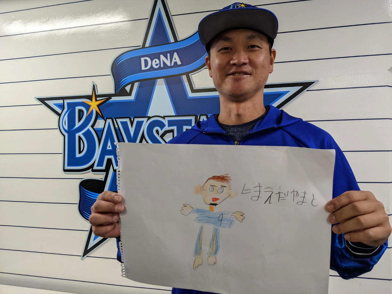 6歳の長男が描いたパパの絵を手に笑顔のDeNA大和（球団提供）