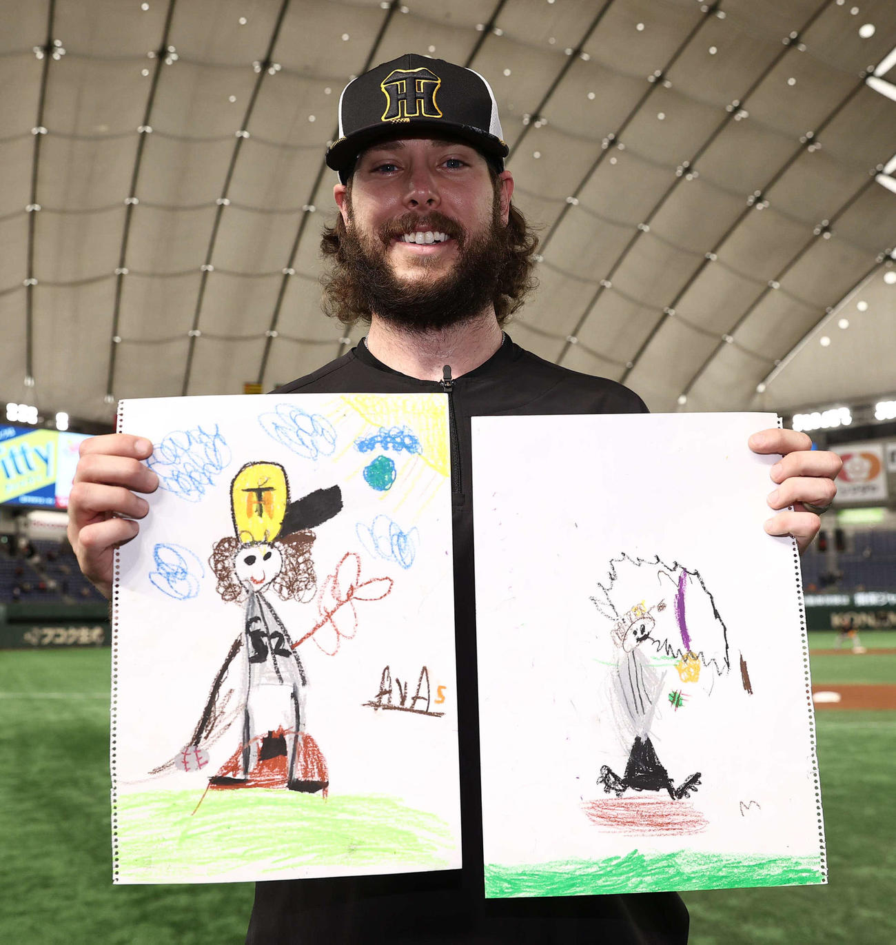 長女エヴァちゃん（左）と長男ボーディー君の書いた絵を持ち笑顔を見せるウィルカーソン（撮影・上田博志）