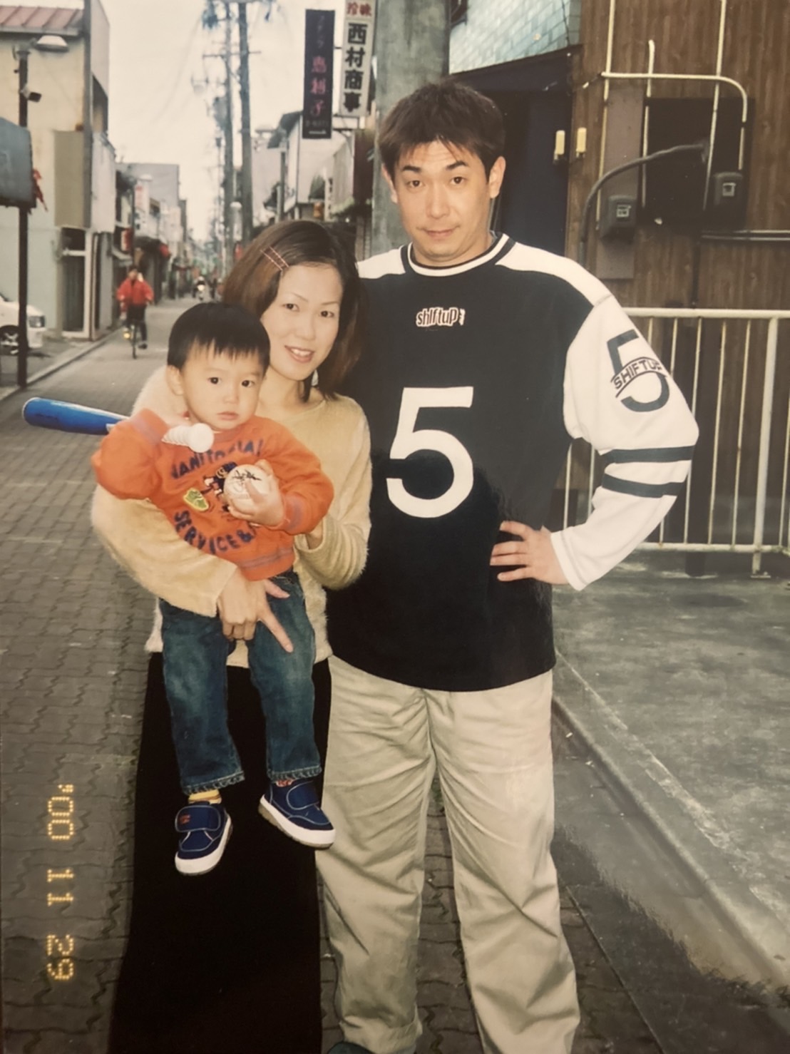 生後1歳4カ月頃の阪神湯浅を抱きかかえる母衣子さん（中央）と父栄一さん（家族提供）