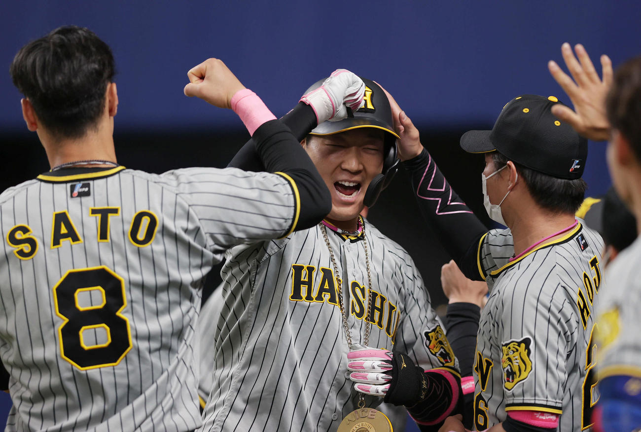 中日対阪神　7回表阪神無死一塁、左中間へ同点となる2点本塁打を放ち、佐藤輝（左）らナインに迎えられる大山（中央）（撮影・前田充）