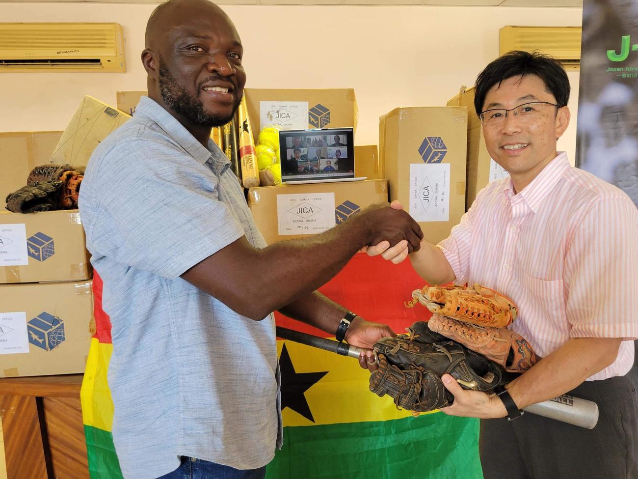 「アフリカ55甲子園プロジェクト」で野球用具を渡す元ガーナ、タンザニア代表監督の友成晋也氏（右）