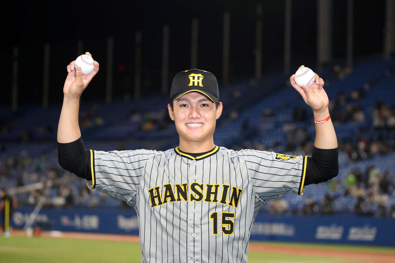 西純は初完投のウイニングボールを右手に、初本塁打の記念ボールを左手に持って笑顔を見せる（撮影・加藤哉）