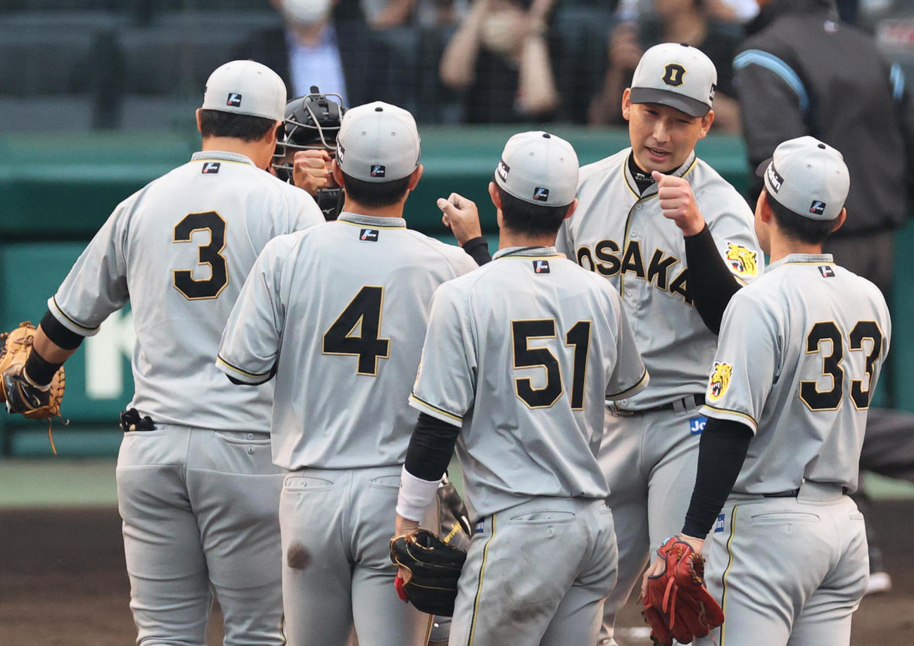 阪神対巨人　試合を締めた阪神岩崎（右から2人目）はナインとタッチを交わす（撮影・上山淳一）