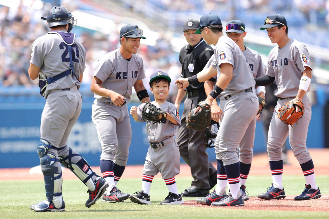 早大対慶大　始球式を務め慶大ナインから祝福される国久さん（中央）（撮影・井上学）