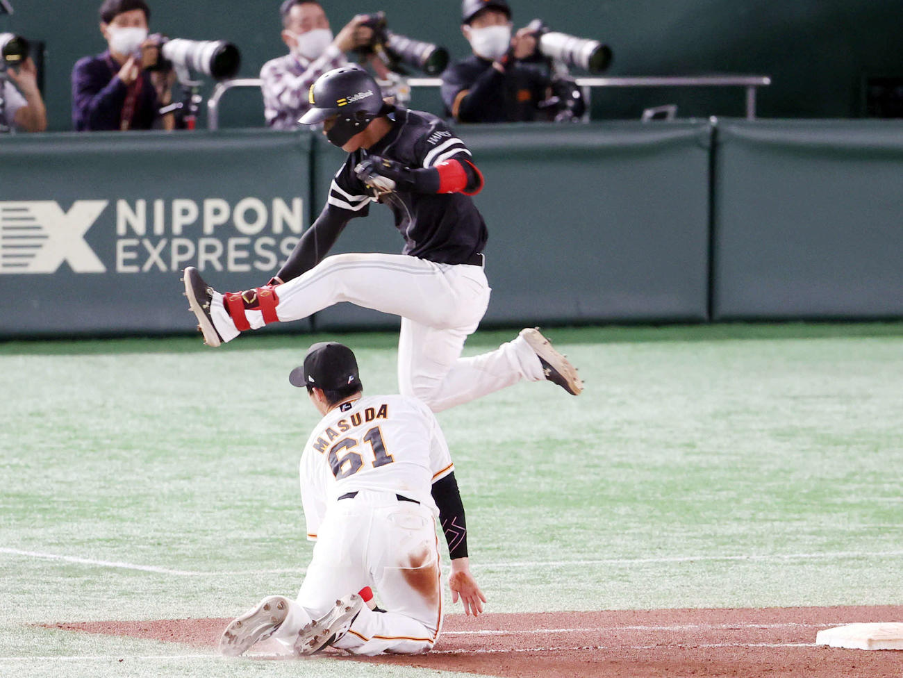 巨人対ソフトバンク　8回表ソフトバンク1死、岡本和の悪送球を捕球した際に体勢を崩した増田陸（下）を避けようとジャンプする今宮（撮影・狩俣裕三）