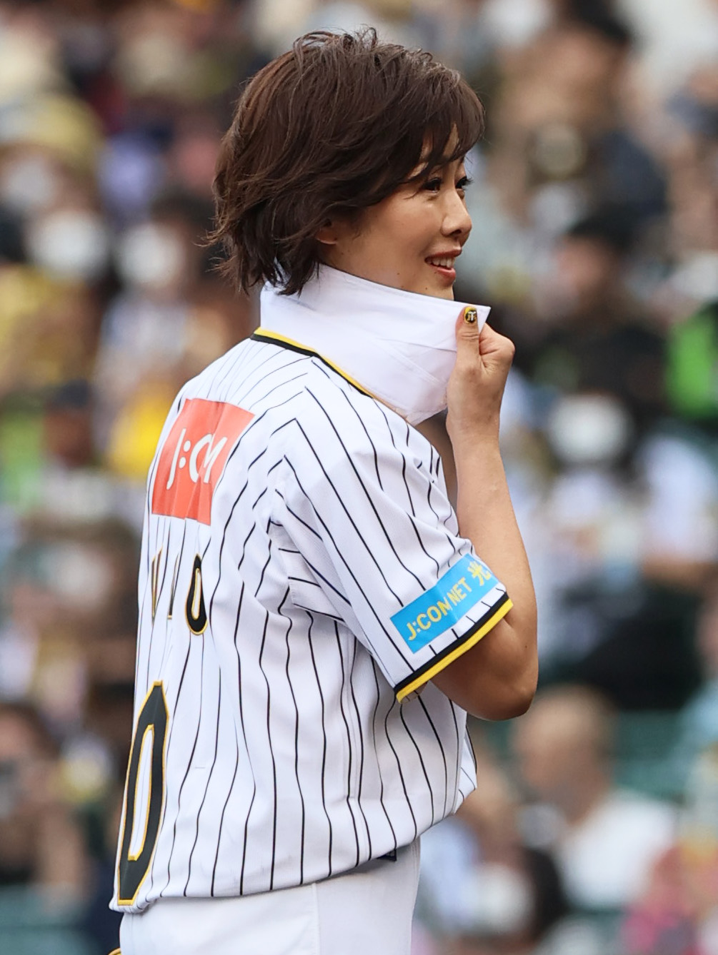 阪神対日本ハム　始球式のマウンドでベンチの日本ハム新庄監督に大きな襟を見せつける有働由美子さん（撮影・上山淳一）