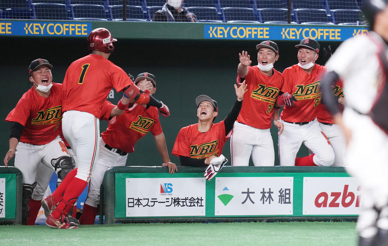松山大対日本文理大　6回裏日本文理大2死二塁、先制の2点本塁打を放った野元（左から2人目）を笑顔で迎えるナイン（撮影・鈴木みどり）