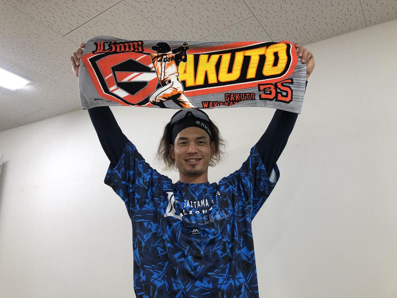 アメコミヒーローをイメージした応援タオルを見せる西武若林