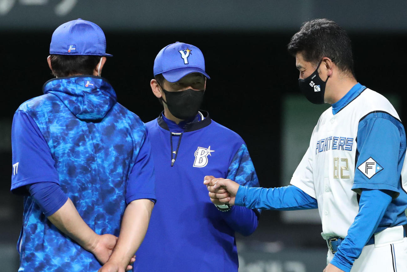 試合前、グータッチを交わすDeNA三浦監督（中央）と日本ハム加藤コーチ（撮影・佐藤翔太）