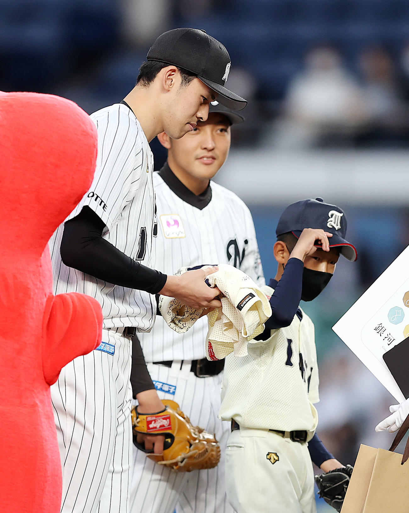 ロッテ対中日　小学生時代に所属していた猪川野球クラブの千葉恭佑君（右）の始球式で打席に立った後、寄せ書き入りのユニホームを手に記念撮影する佐々木朗（撮影・狩俣裕三）