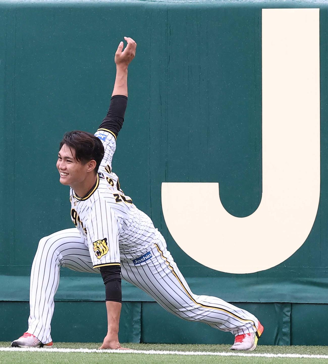 6月6日、笑顔でストレッチする阪神西純矢