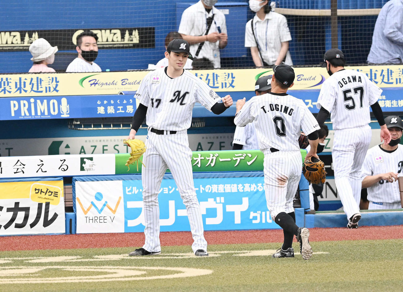 8回を投げ終えベンチ前でロッテ荻野（手前右）とタッチをかわす佐々木朗希（撮影・滝沢徹郎）