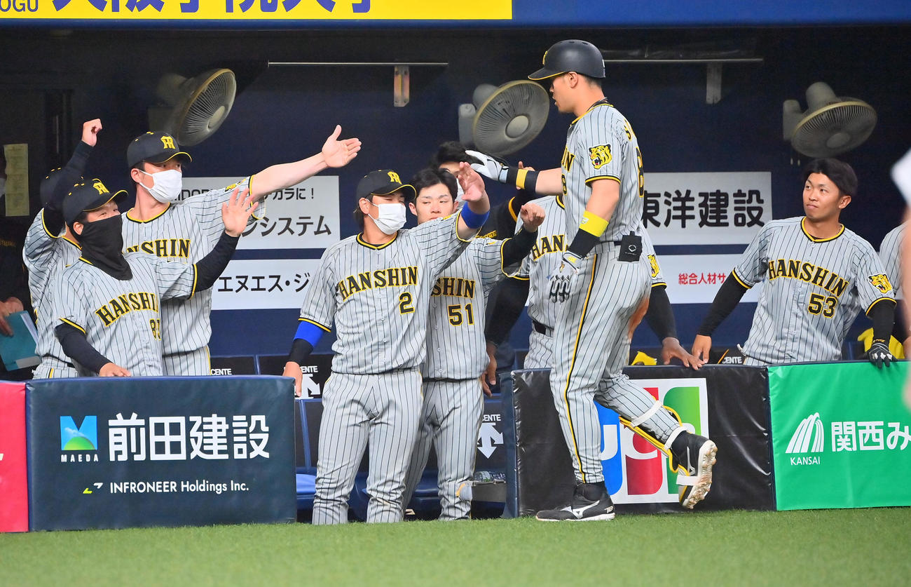 オリックス対阪神　7回表阪神1死一、二塁、右中間を破る2点適時打を放った佐藤輝はベンチのナインに迎えられる（撮影・和賀正仁）