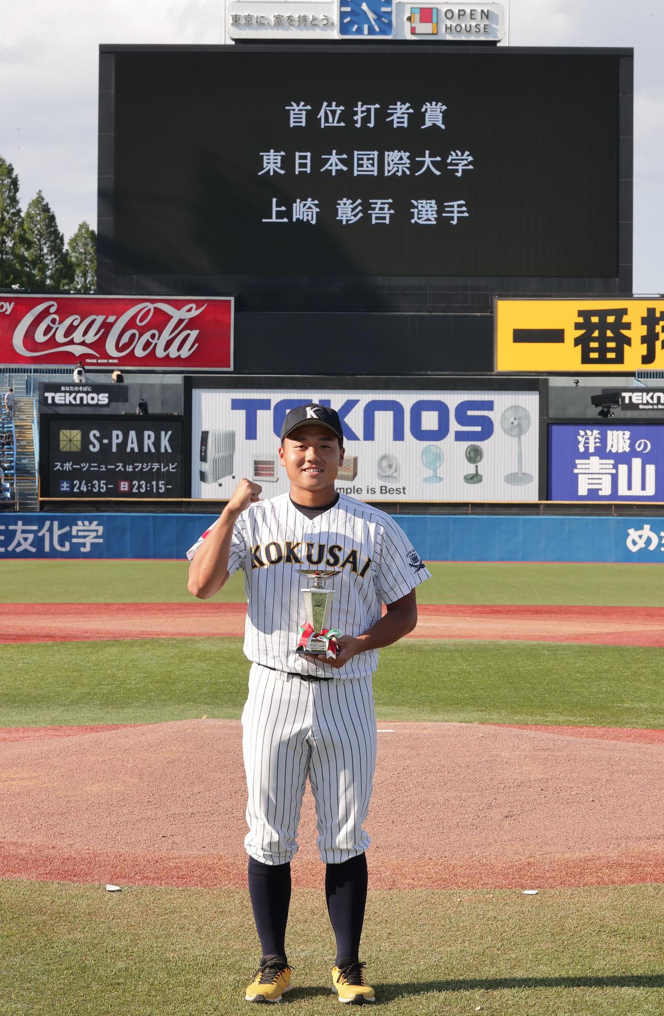 首位打者賞を受賞し、トロフィーを手にガッツポーズの東日本国際大・上崎（撮影・野上伸悟）
