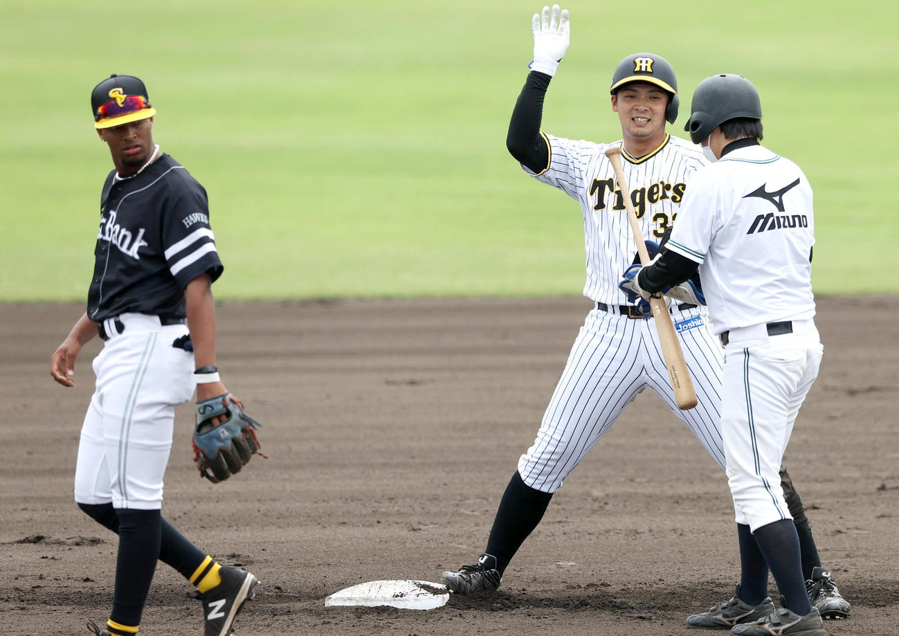 練習試合・阪神2軍対ソフトバンク3軍　6回裏阪神無死、井上（右）は中へ二塁打を放ちベンチの祝福に笑顔で手を挙げる。左は遊撃手ヘラルディーノ（撮影・上山淳一）