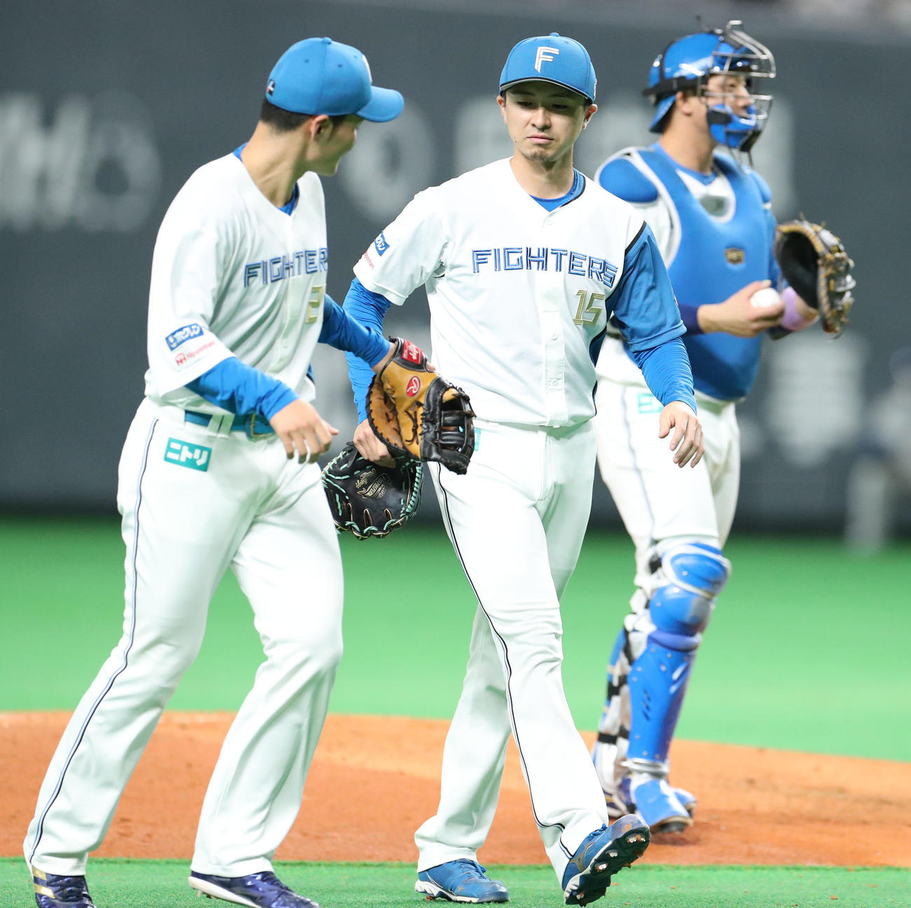 日本ハム対ロッテ　5回表ロッテ2死一塁、一走高部をけん制でアウトにしタッチを交わしながらベンチに戻る清宮（左手前）と上沢（撮影・佐藤翔太）