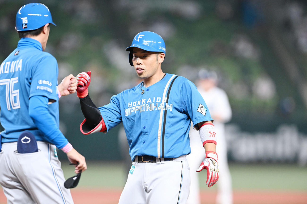 西武対日本ハム　2回表日本ハム1死二塁、中前適時打を放った近藤（右）は紺田コーチとタッチを交わす（撮影・滝沢徹郎）