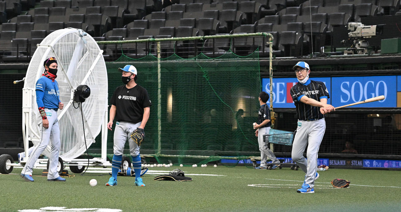 西武対日本ハム　試合前練習でノックする日本ハム山田バッテリーコーチ（右）を見守る新庄監督（左）（撮影・滝沢徹郎）