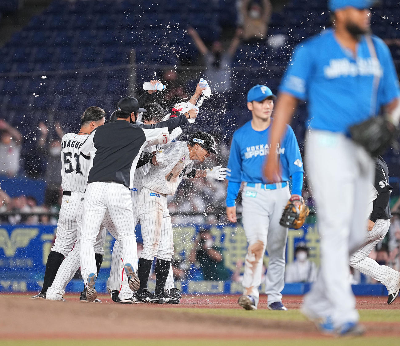 ロッテ対日本ハム　10回裏ロッテ1死三塁、左前にサヨナラの適時打を放ち、ウォーターシャワーを浴びる荻野貴（中央）。右端はロドリゲス、右から2人目は清宮（撮影・菅敏）