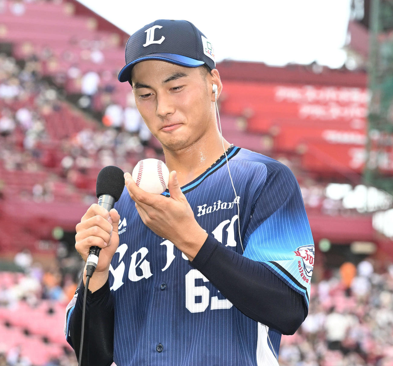 楽天対西武　ヒーローインタビューでプロ初安打の記念球を見つめる西武長谷川（撮影・滝沢徹郎）