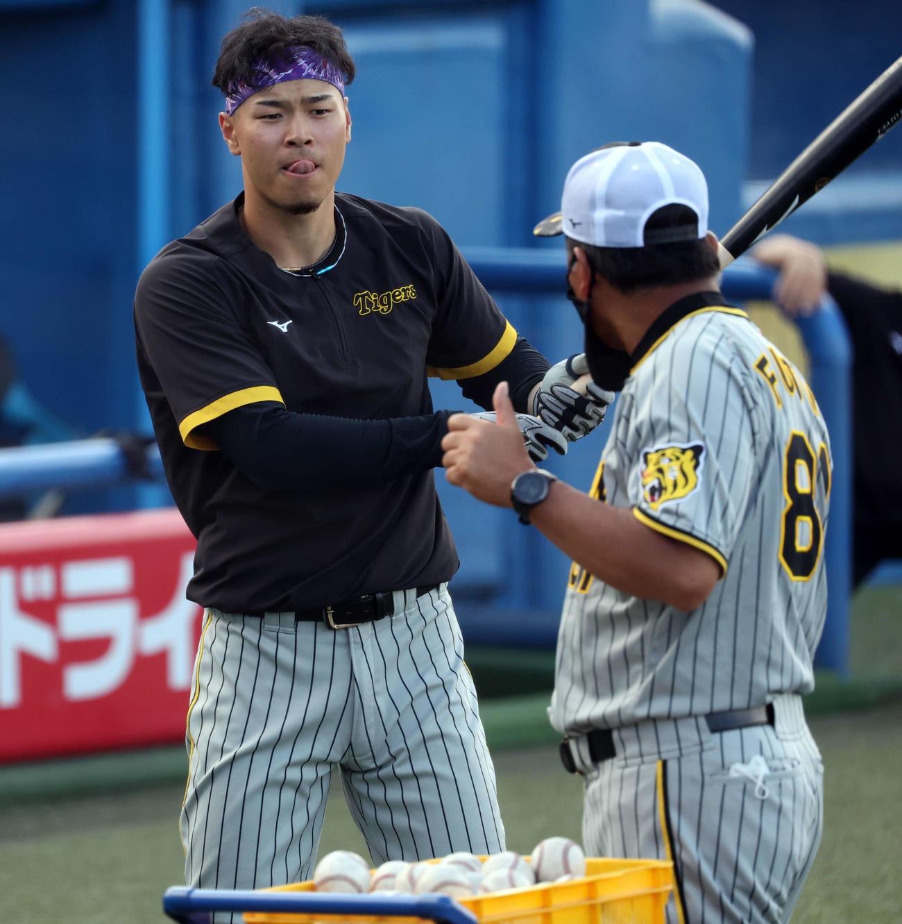 ヤクルト対阪神　ティー打撃中、藤井コーチ（手前）から指導を受ける佐藤輝（撮影・浅見桂子）