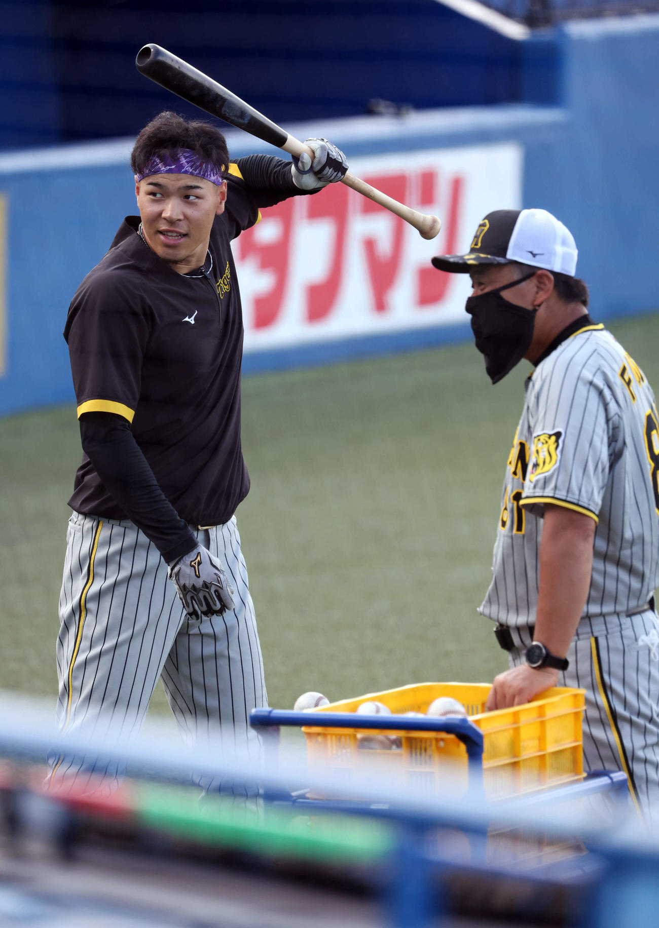 ティー打撃中、藤井コーチ（手前）から指導を受ける佐藤輝（撮影・浅見桂子）