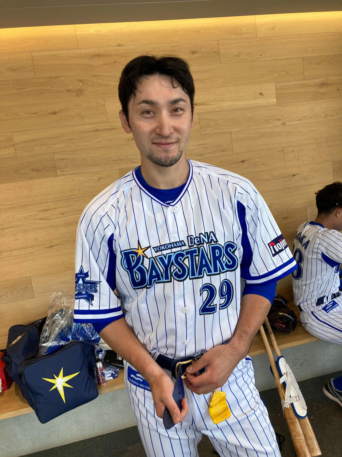 ユニホームの着替え中に笑顔をみせるDeNA伊藤。ベルト下の黄色いものがお守りです（球団提供）